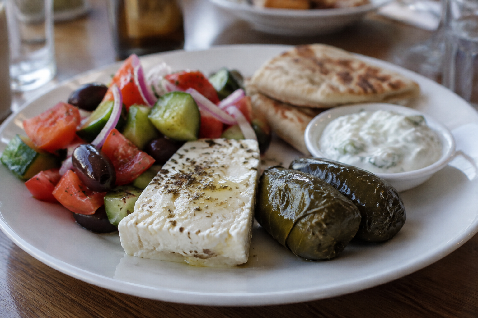 Assiette grecque composée de salade grecque, feta, feuille de vigne farcie, tzatziki et pain pita