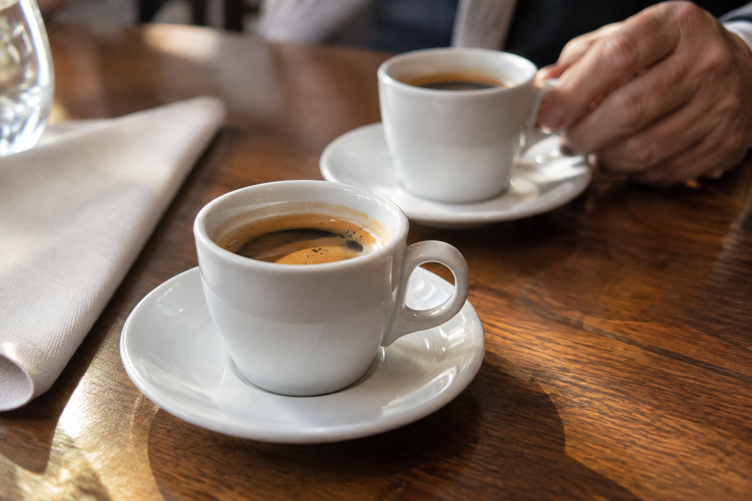 Deux tasses de café sur leurs soucoupes, posées sur une table en bois, pour le café de bienvenue.